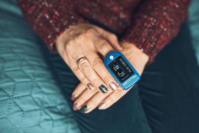 Woman measuring the degree of oxygen saturation of the blood at home using pulse oximeter