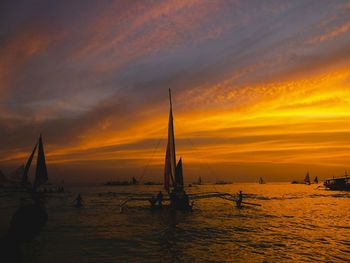 Silhouette sailboats in sea against sky during sunset