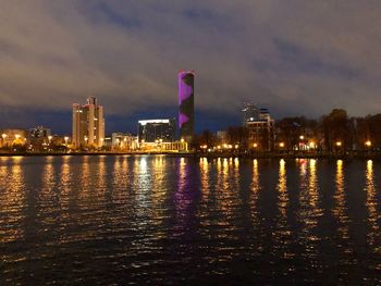 River by illuminated buildings against sky at night