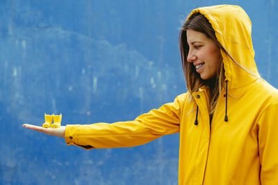 Woman holding rubber boot in hand against blue background