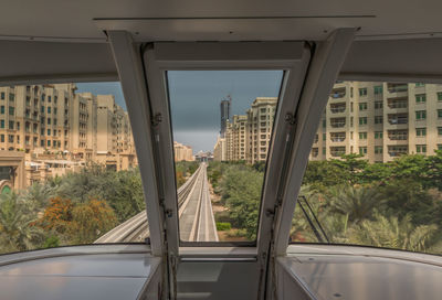 Buildings in city against sky seen through glass window