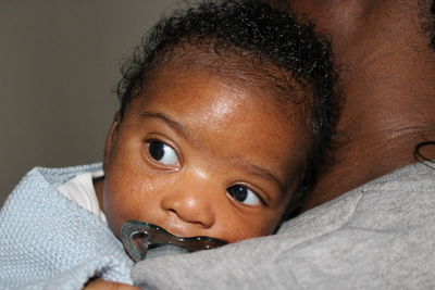 Close-up portrait of cute baby relaxing on mother's shoulder 