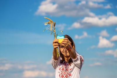 Low angle view of girl blowing bubbles against sky