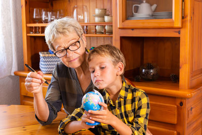 Homeschooling grandmother teaching kid, child, smart boy in geography. happy family, education