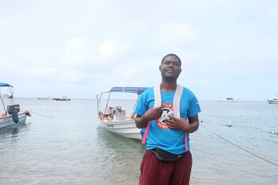 Young man standing in sea against sky