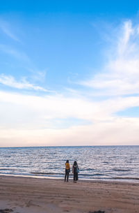 People standing on beach against sky