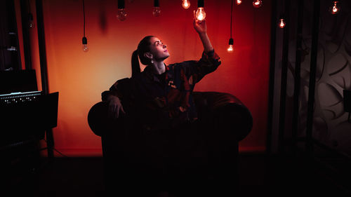 Woman sitting in chair touching pendant light