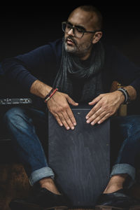 Midsection of man sitting against black background