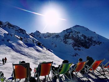 People on snowcapped mountains against clear sky during sunny day