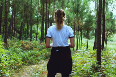 Rear view of woman standing in forest