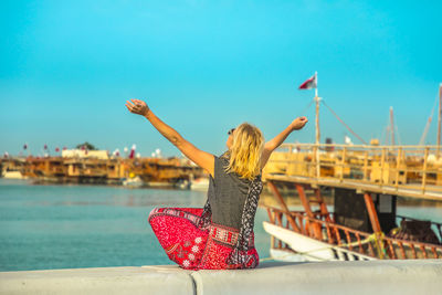 Woman sitting at beach against clear sky