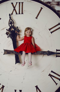 Girl sitting on clock hand
