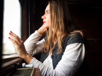 Young woman looking through window while traveling in train