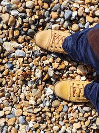 Low section of man standing on pebbles