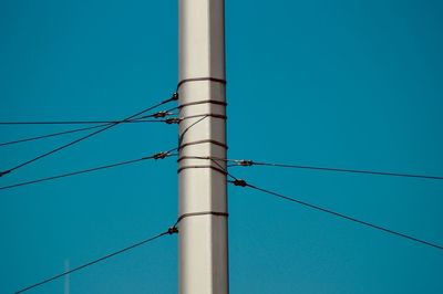 Low angle view of electricity pylon against blue sky