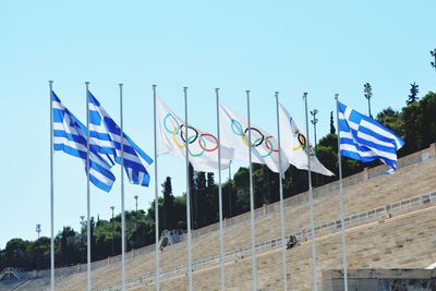 Low angle view of flags against clear blue sky