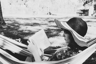 Woman reading book while relaxing in hammock