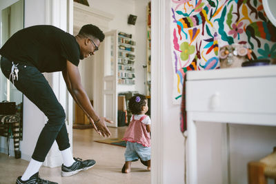 Smiling young man walking behind daughter at home