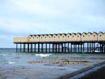 Built structure on beach by sea against sky