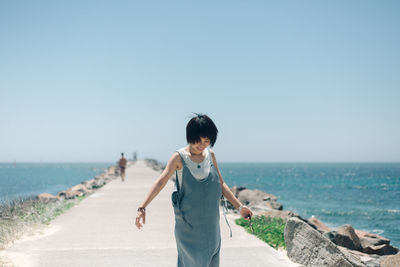 Full length of woman standing on beach against clear sky