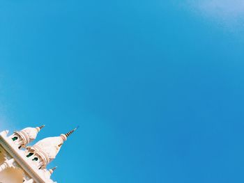 Low angle view of birds flying against clear blue sky