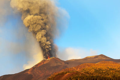 Smoke emitting from volcanic mountain against sky