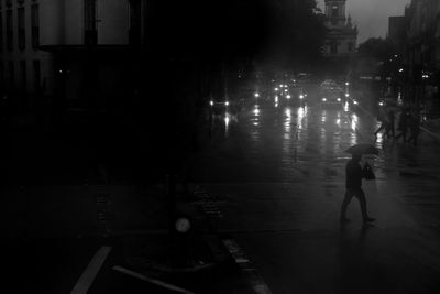 Silhouette man walking on illuminated street at night