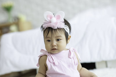 Close-up cute baby girl wearing headband sitting at home