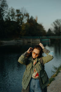 A young woman standing next to a river during sunset