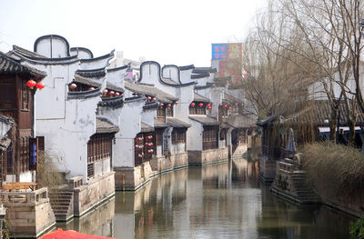 Canal amidst buildings in city against sky