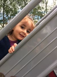 Portrait of cute girl looking through gray metallic railing