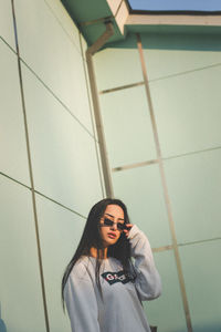 Portrait of smiling young woman standing against wall