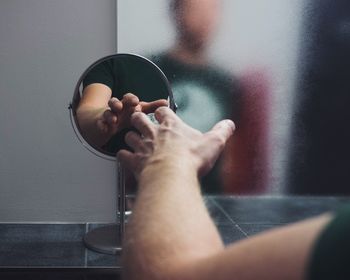 Man touching mirror in bathroom