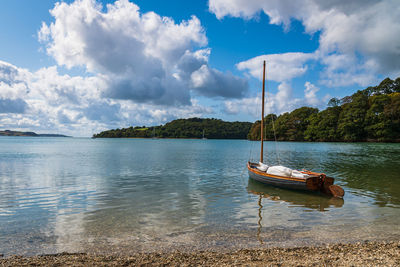 Sailboats moored on lake against sky