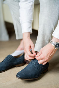 Low section of man tying shoelace