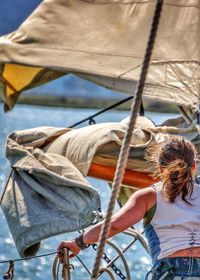 Rear view of woman standing on sailboat