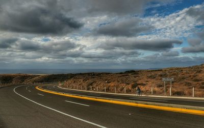 Country road against cloudy sky