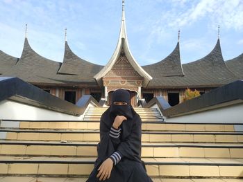 Midsection of man photographing with building in background
