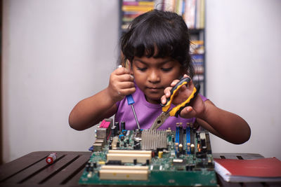 Little girl playing with motherboard computer at home