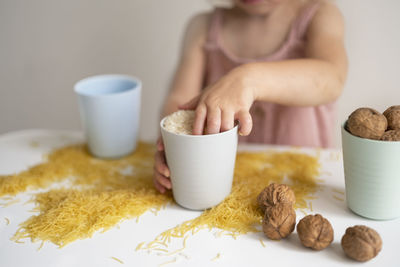Baby hands playing with grain, nuts, pasta and rice at table.sensorial early development