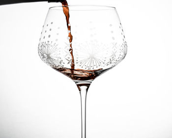 Close-up of wineglass on glass against white background