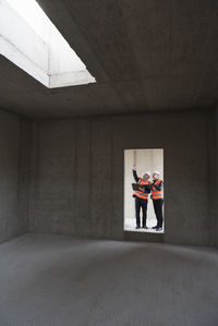 Two men wearing safety vests talking in building under construction