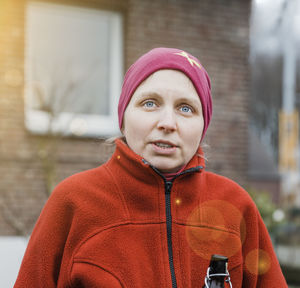 Woman wearing warm clothing looking away while standing against house