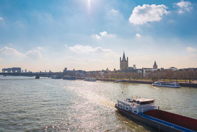 View of buildings by river against cloudy sky