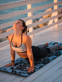 Full length of woman doing yoga on promenade during sunrise