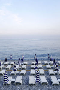 High angle view of deck chairs with parasols at beach against sky