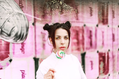 Portrait of beautiful young woman standing against pink wall