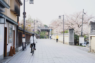 Rear view of woman walking on footpath amidst buildings