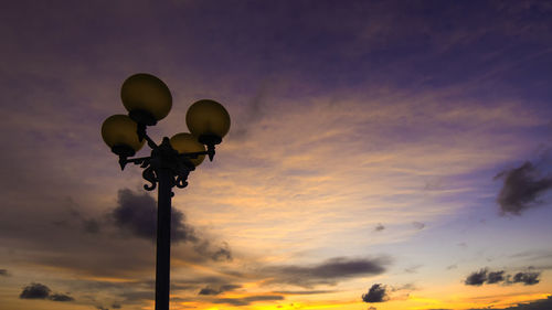 Low angle view of street lights against sky during sunset