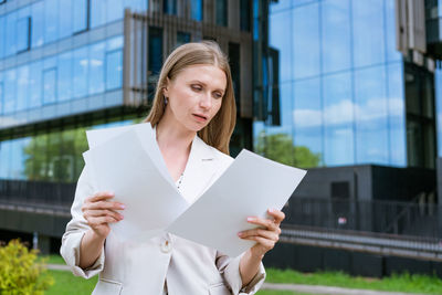 Young woman holding camera in front of building